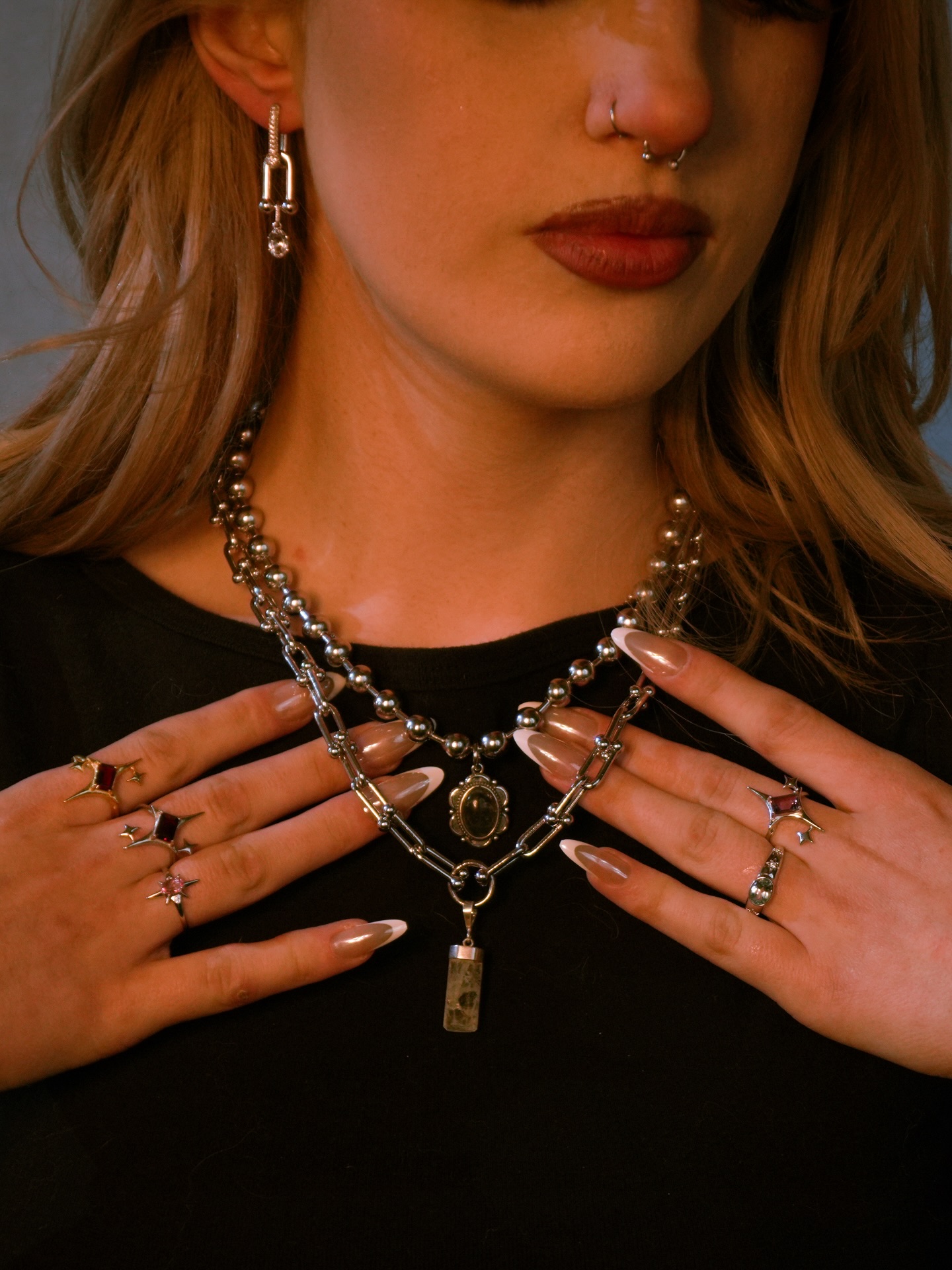 Layered silver chains with crystal pendants, star rings set with garnet and pink stones, and a crystal drop earring